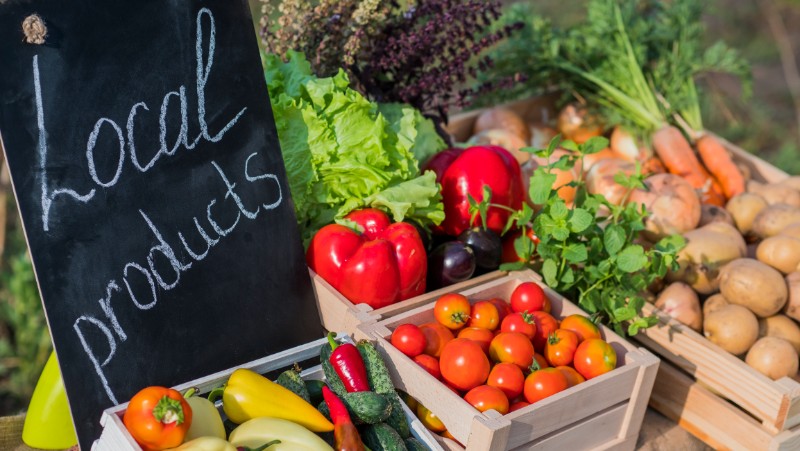 Counter with fresh vegetables and a sign of local products