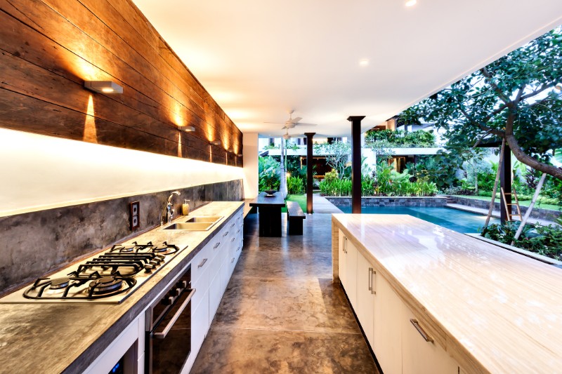 Outdoor kitchen with a stove an countertop next to garden